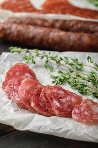 Variété de chorizo séché à sec, fuet et autres saucisses coupées en tranches avec des herbes sur la vieille table en bois