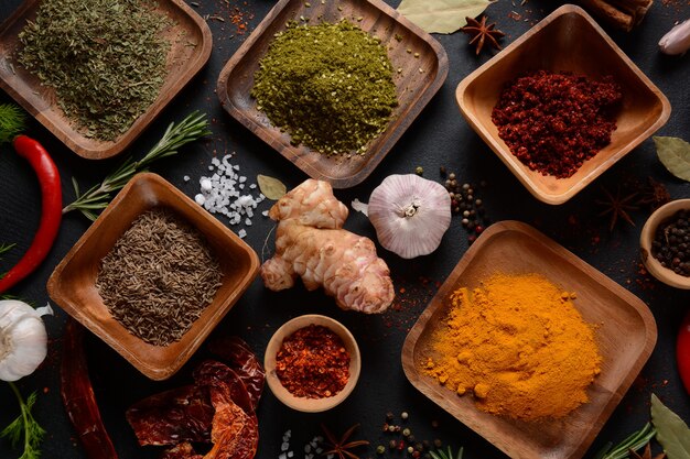 Variété d'épices et d'herbes sur la table de la cuisine. Diverses herbes et épices colorées pour la cuisson sur fond sombre