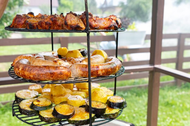 Variété de grillades de viande et de légumes sur un grill contre un espace de copie de clôture en bois