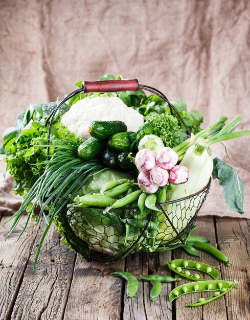 Variété de légumes dans un panier métallique sur un fond en bois