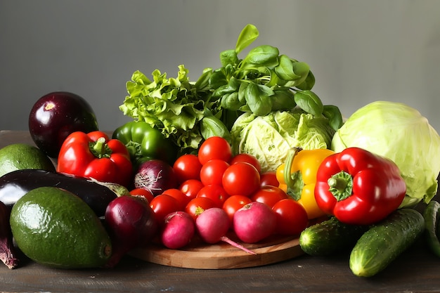 Variété de légumes frais poivre, radis, avocat, brocoli, aubergine, chou, tomate, oignon rouge sur une planche