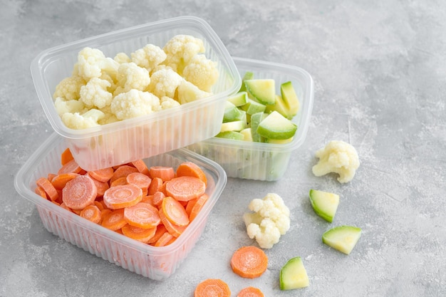 Une Variété De Légumes Surgelés Dans Des Récipients En Plastique Sur Un Fond De Béton Gris