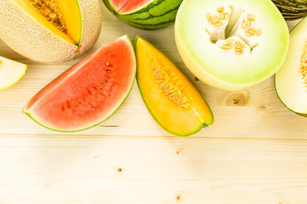 Variété de melons biologiques tranchés sur table en bois.