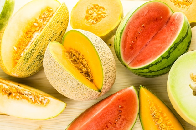 Variété de melons biologiques tranchés sur table en bois.