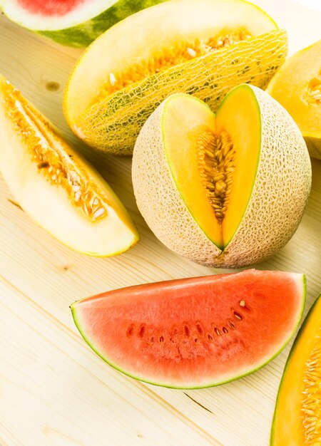 Variété de melons biologiques tranchés sur table en bois.