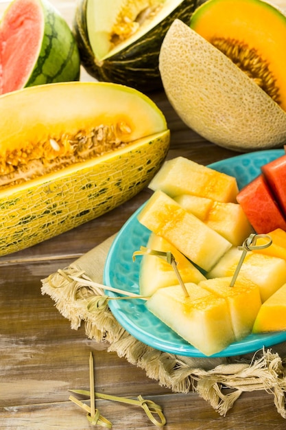 Variété de melons biologiques tranchés sur table en bois.