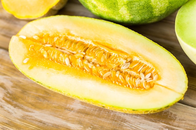 Variété de melons biologiques tranchés sur table en bois.