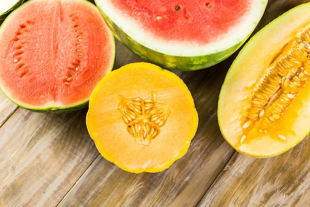 Variété de melons biologiques tranchés sur table en bois.