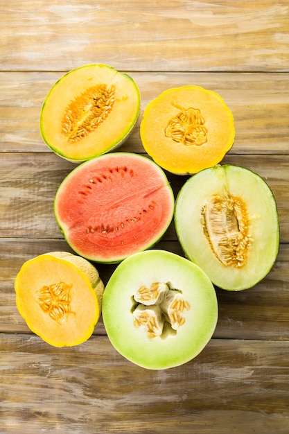 Variété de melons biologiques tranchés sur table en bois.