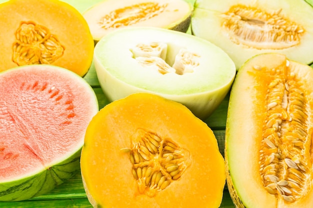 Variété de melons biologiques tranchés sur table en bois.