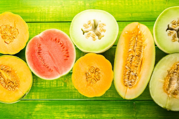 Variété de melons biologiques tranchés sur table en bois.