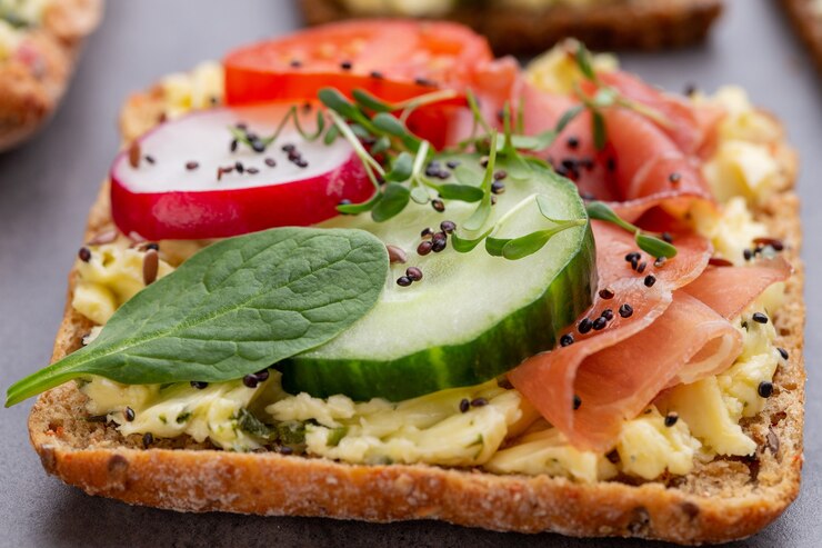 Variété de mini sandwichs avec fromage à la crème, légumes et salami.