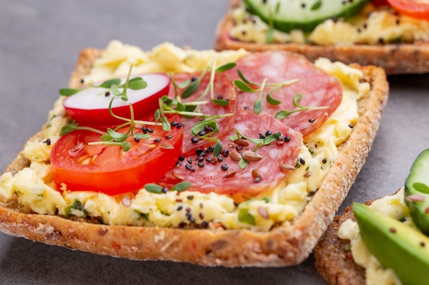 Variété de mini sandwichs avec fromage à la crème, légumes et salami.