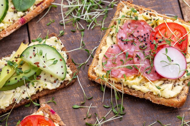 Variété de mini sandwichs avec fromage à la crème, légumes et salami.