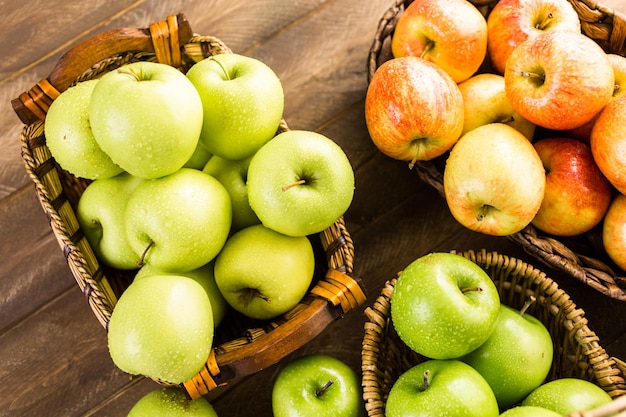 Variété de pommes biologiques dans des paniers sur table en bois.