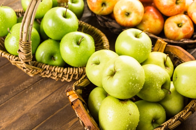 Variété de pommes biologiques dans des paniers sur table en bois.