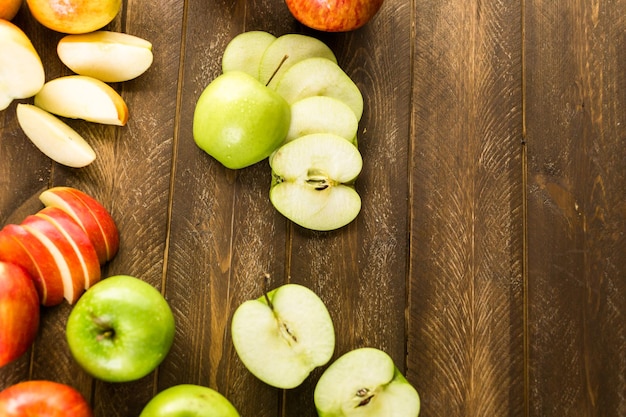 Variété de pommes biologiques tranchées sur table en bois.