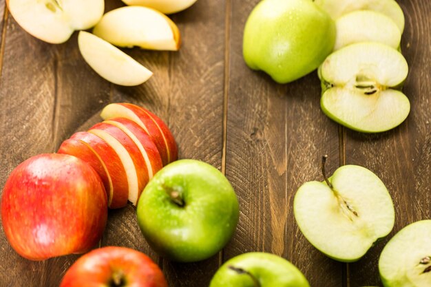 Variété de pommes biologiques tranchées sur table en bois.