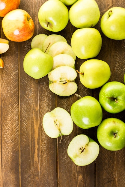 Variété de pommes biologiques tranchées sur table en bois.