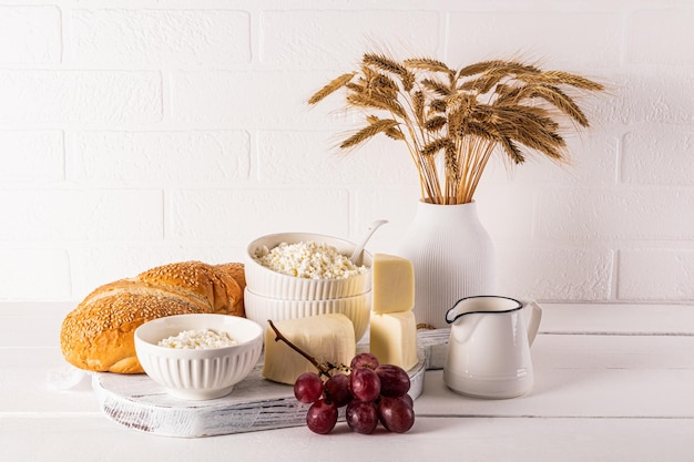 Photo une variété de produits laitiers frais pain raisins épis de maïs sur une table en bois friandises et symboles de la fête juive de shavuot
