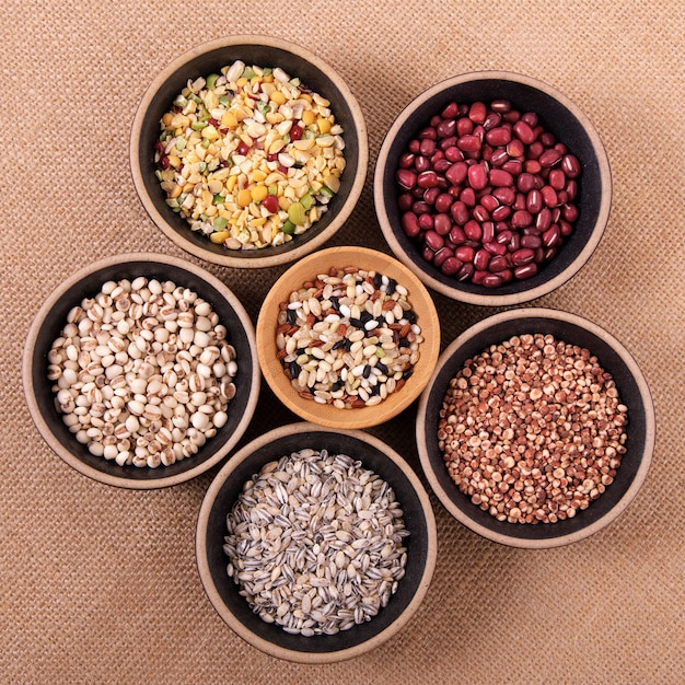 Variété de riz et de céréales dans des bols sur la nappe de lin