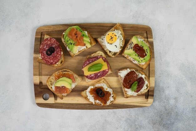 Variété de sandwichs à tapas pour l'apéritif sur bois sur fond gris