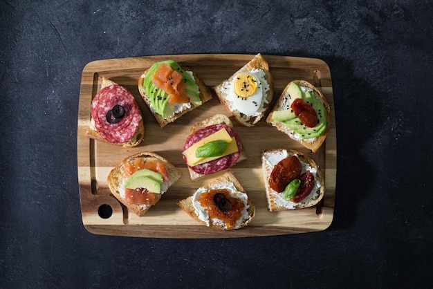 Variété de sandwichs à tapas pour l'apéritif sur bois sur fond noir Vue de dessus