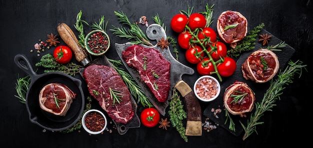 Variété de steaks de viande crue black angus prime rumsteck de boeuf, filet mignon de filet mignon ou grillades avec assaisonnement sur fond noir. bannière, vue de dessus de recette de menu.