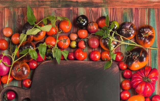 Variété de tomates colorées fraîches et planche à découper en bois L'agriculture biologique est écologique