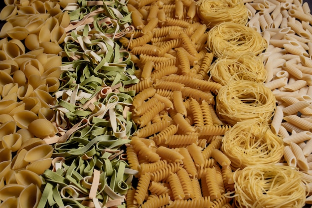 Variété de types et de formes de pâtes italiennes sèches. Fond de nourriture crue de macaroni italien ou texture: pâtes, spaghettis, pâtes en forme de spirale.