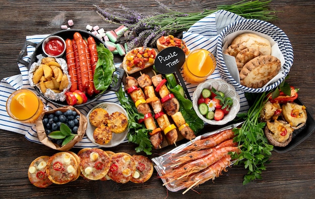 Variétés de repas grillés viandes grillées légumes fruits salade et pommes de terre sur un fond en bois foncé vue du haut