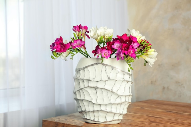 Vase avec de belles fleurs de freesia sur table