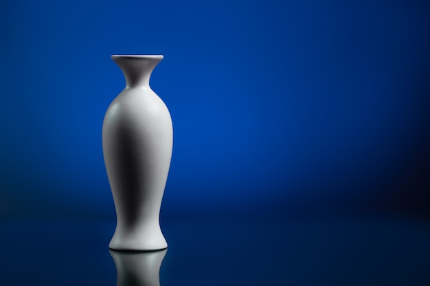 Vase blanc sur fond bleu. Surface du miroir