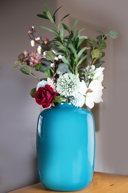Vase bleu élégant avec décoration moderne de faux arrangement de fleurs dans une maison de luxe sur table en bois, beauté