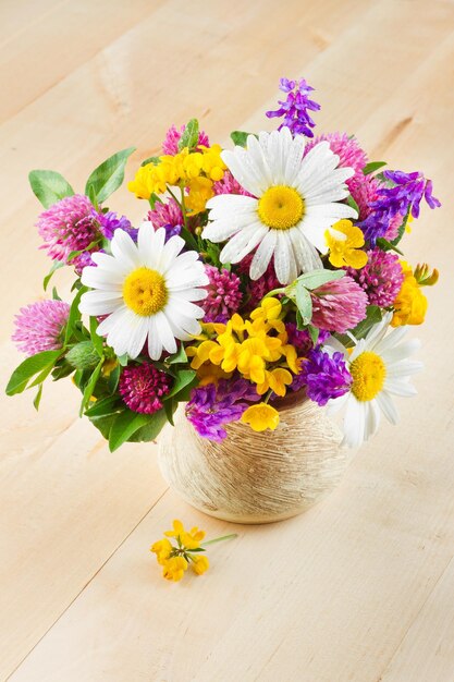 Vase avec bouquet d'herbes médicinales et de fleurs sur table en bois