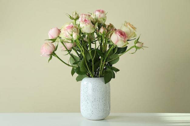 Vase avec bouquet de roses sur table blanche