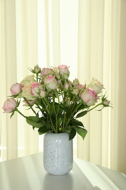 Vase avec bouquet de roses sur table blanche