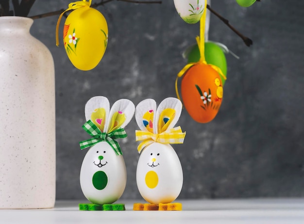 Vase avec des branches décorées d'oeufs de Pâques Lapins drôles faits de coquilles d'oeufs Espace de décoration de Pâques pour un texte