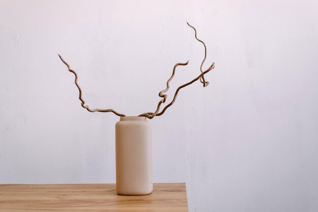 Vase avec brindilles nues sur table en bois