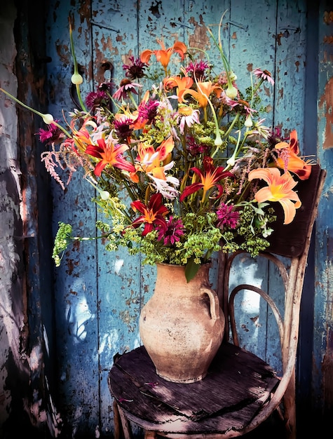 Un vase de fleurs est assis sur une table avec un fond bleu