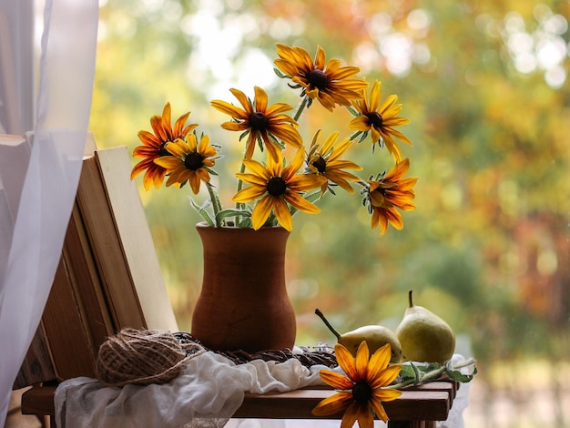 Vase avec des fleurs jaunes et des livres sur le fond de la nature d'automne Nature morte d'automne