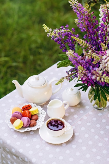 Un vase avec des fleurs de lupin, une théière et une tasse de thé sur un plateau en bois