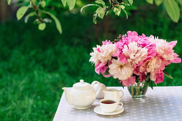 Un vase de fleurs de pivoines près d'une tasse de café