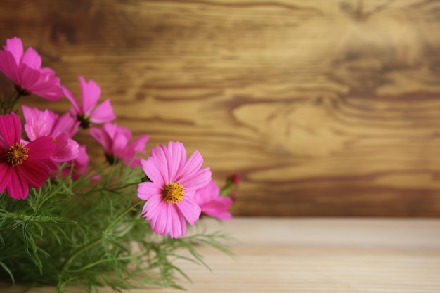 Un vase de fleurs roses sur une table en bois