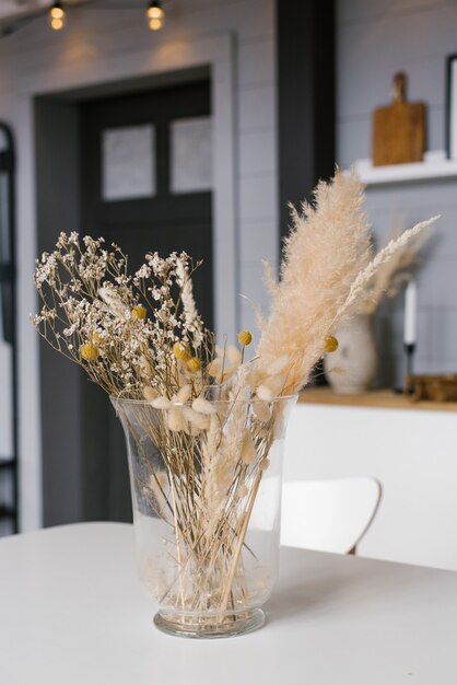Un vase de fleurs séchées sur la table. Chambre classique scandinave avec des détails en bois et blancs, un design intérieur minimaliste. maison confortable.