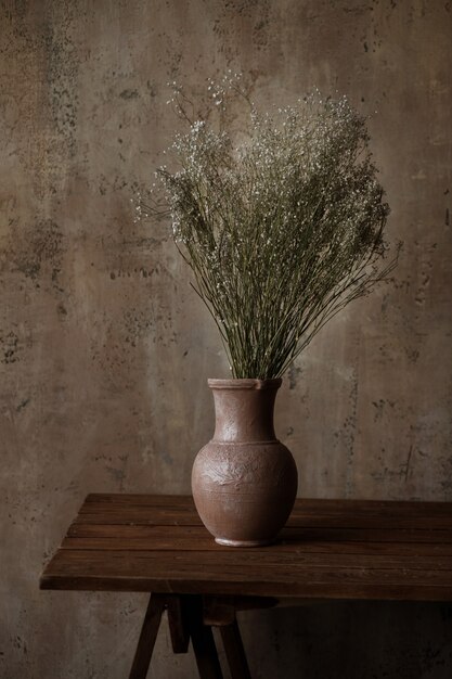 vase avec des fleurs séchées sur une table marron.