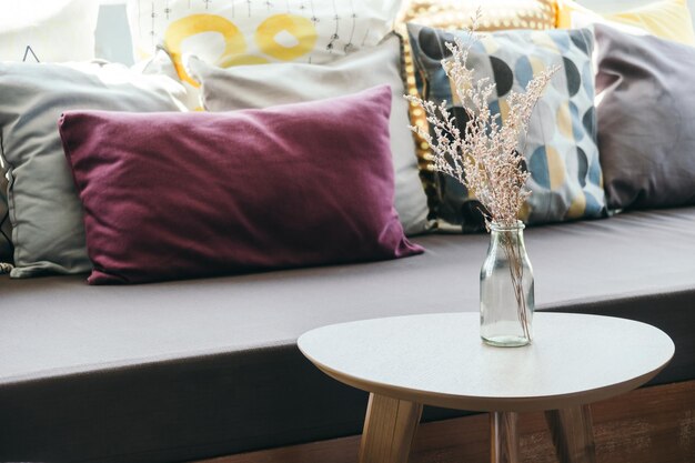 Photo vase de fleurs sur la table par les oreillers sur le canapé à la maison