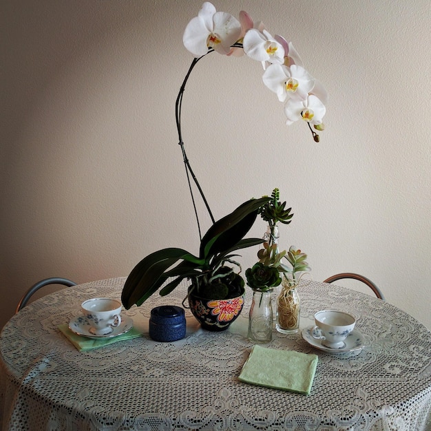 Photo vase à fleurs avec des tasses à café sur la table contre le mur