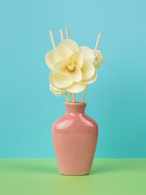 Vase rose pour aromathérapie avec étagères et une grande fleur sur fond vert et bleu