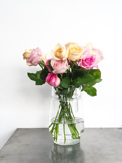Un vase de roses est sur une table avec de l'eau dedans.